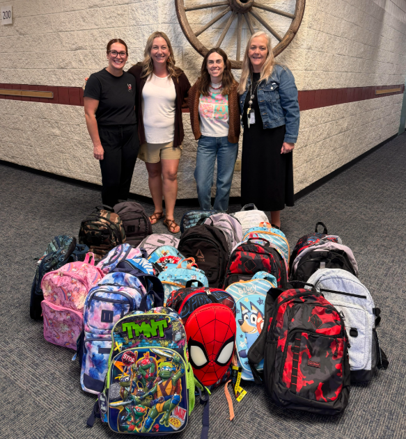 Teachers smiling with donated backpacks & supplies!
