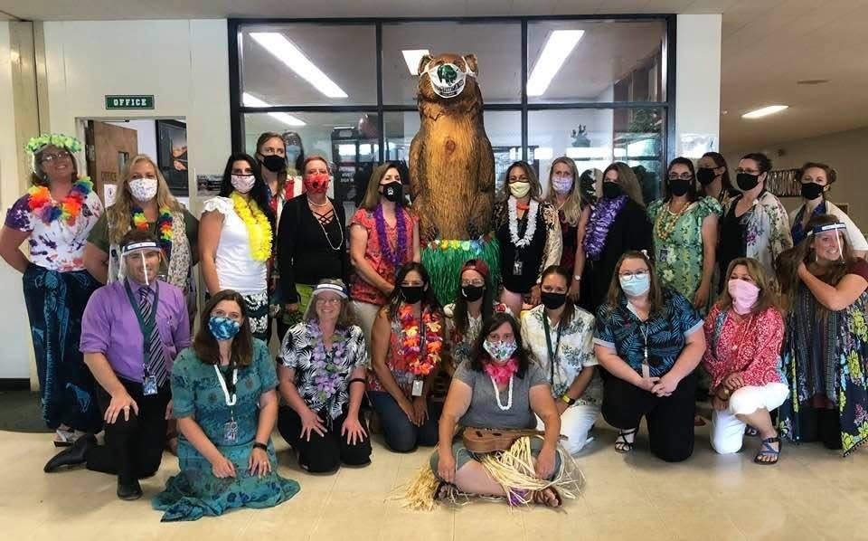a picture of a school staff wearing masks and Hawaiian outfits 