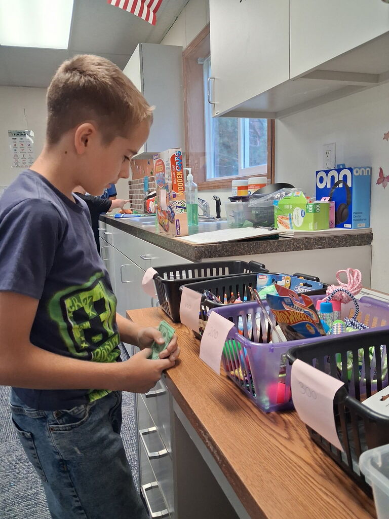 A boy is standing and examining an item while standing at a counter with storage baskets.