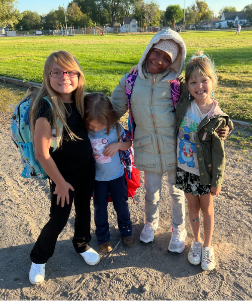 Four children stand together excited for the first day of school!