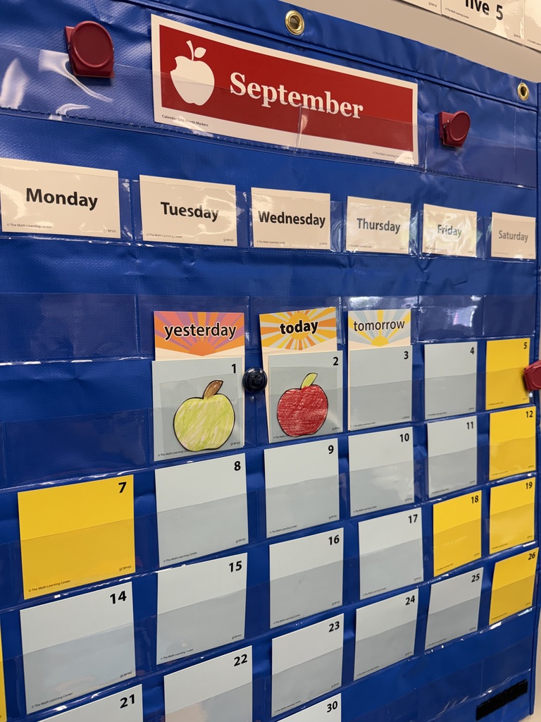 A blue bulletin board with a red apple logo and "September" at the top. Days of the week are listed with yellow and white cards. Fruit icons mark specific days.