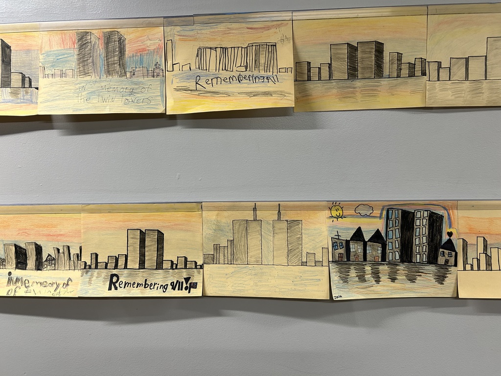 Three pieces of artwork attached to a wall. They show cityscapes in yellow and orange tones.