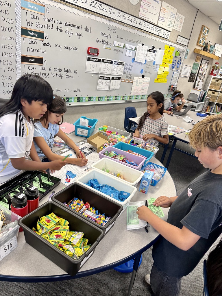 Children in a classroom gathered around a table with various colored candies, possibly learning about math and counting.