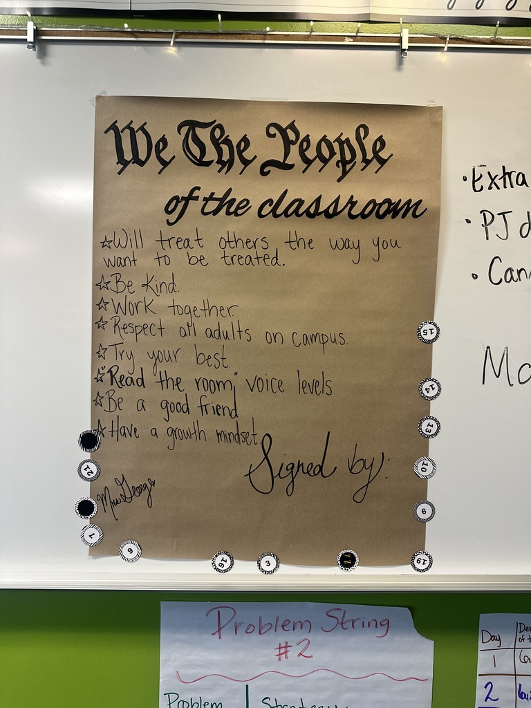 A classroom whiteboard with a pinned paper displaying "We The People of the Classroom." It lists rules like "Be Kind" and "Respect all adults." Below it, another paper reads "Problem Solving."