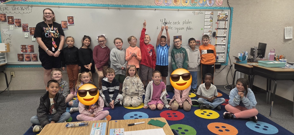 Classroom with students, one wearing a face mask, smiling and posing for a photo.