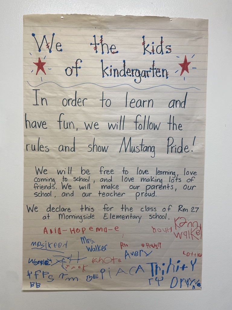 A handwritten note on paper displays a pledge with the heading "We the kids of kindergarten." It includes a red star and text about rules and pride.