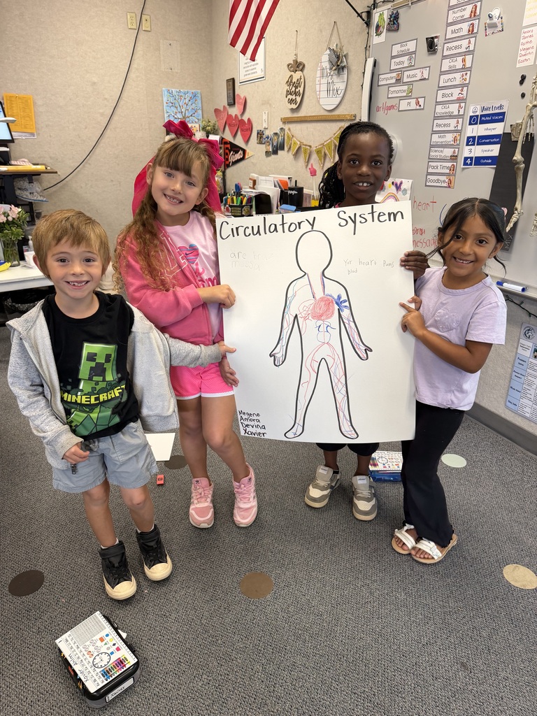 Four children hold up a large white poster with a diagram of the human body.