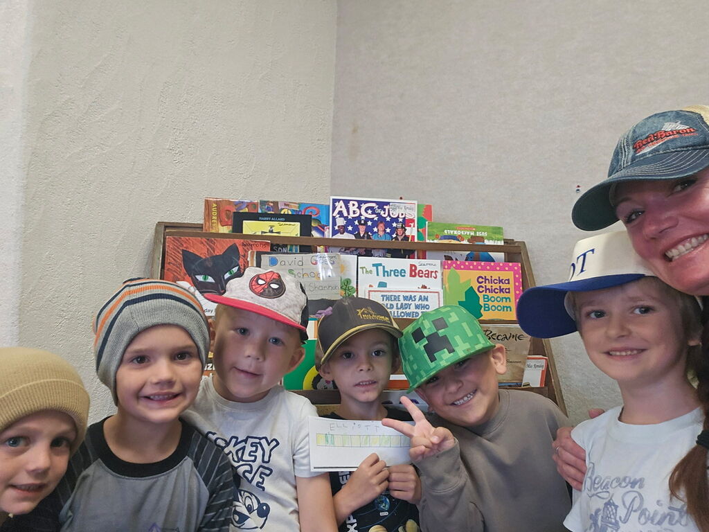 A group of children in hats in a room with a bookshelf in the background.