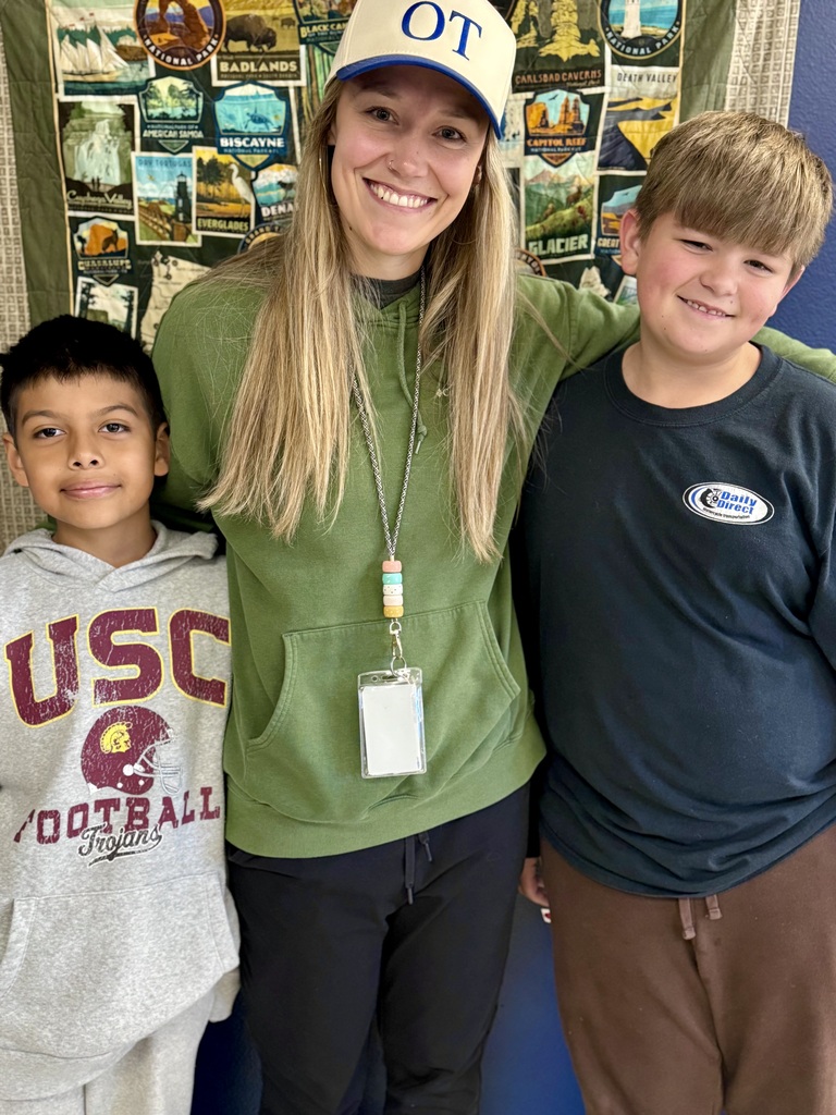 A woman and two children pose for a photo, smiling. They stand against a colorful background.