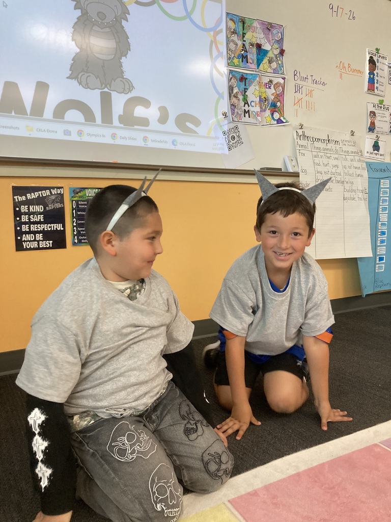 Two young boys in school uniforms sit on the floor with paper ears on their heads.