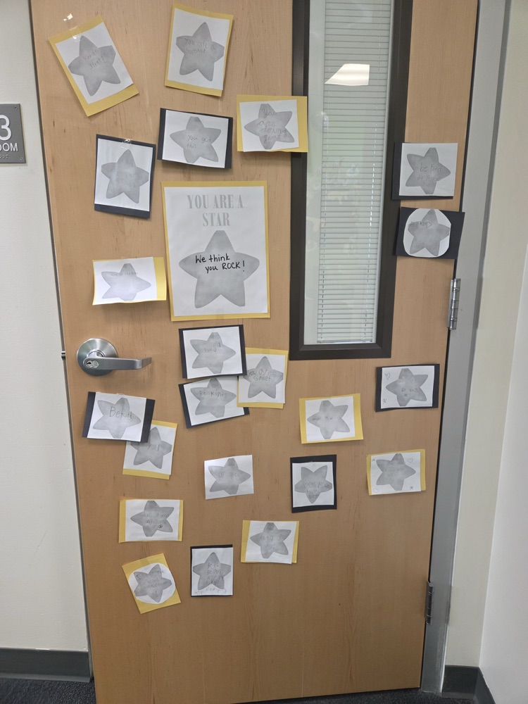 A wooden door covered with star-shaped stickers. A message reads, "You are a star."
