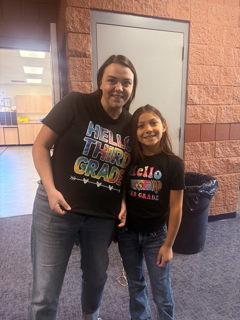 Two people stand next to each other, smiling. A woman in a black shirt and jeans, and a girl in a similar black shirt.