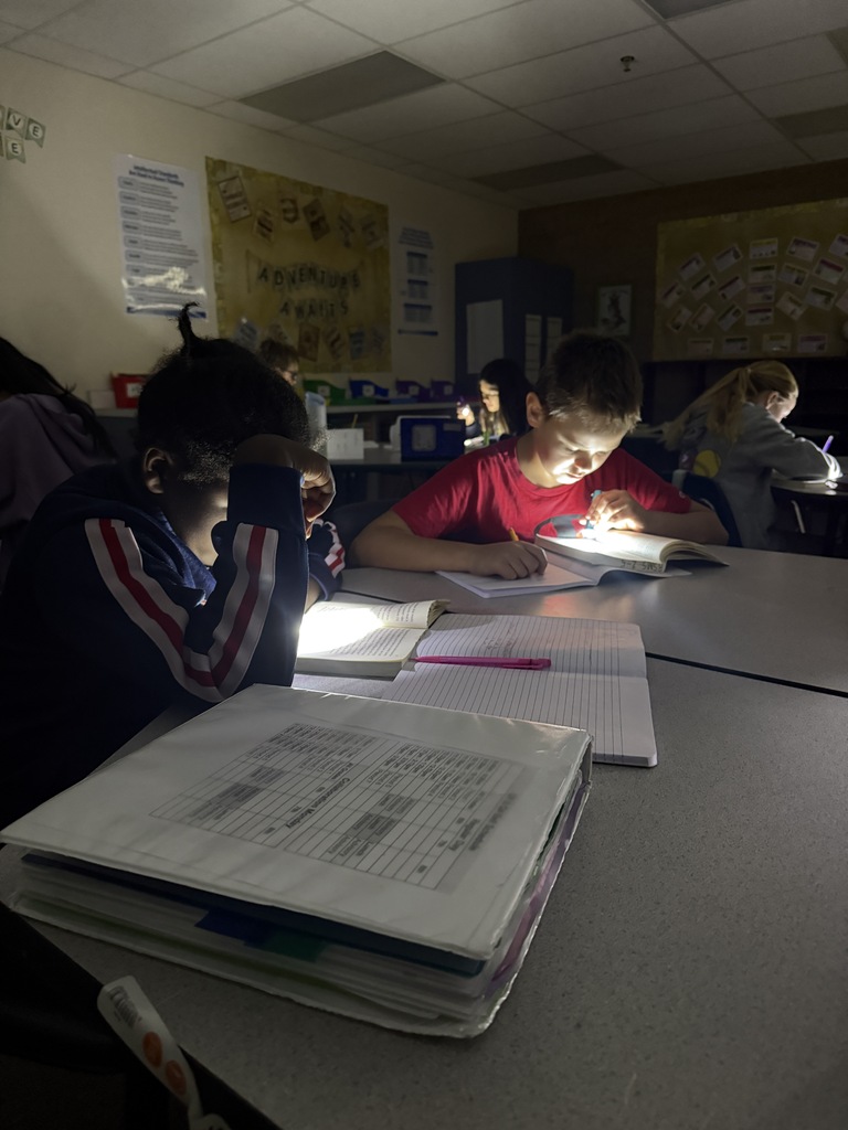 a picture of two students reading at a table with a flashlight