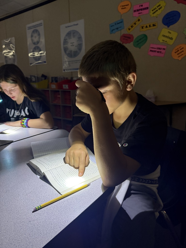a picture of two students reading at a table with a flashlight