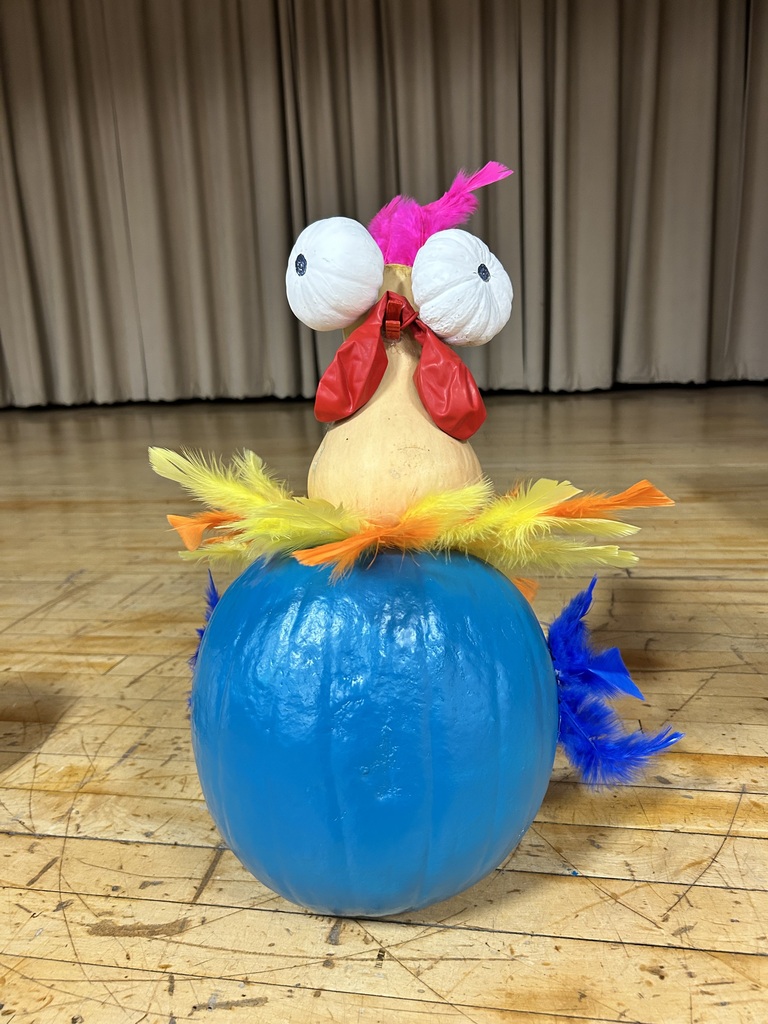 A pumpkin with a painted bird sitting on it, the bird has large white eyes and colorful feathers.