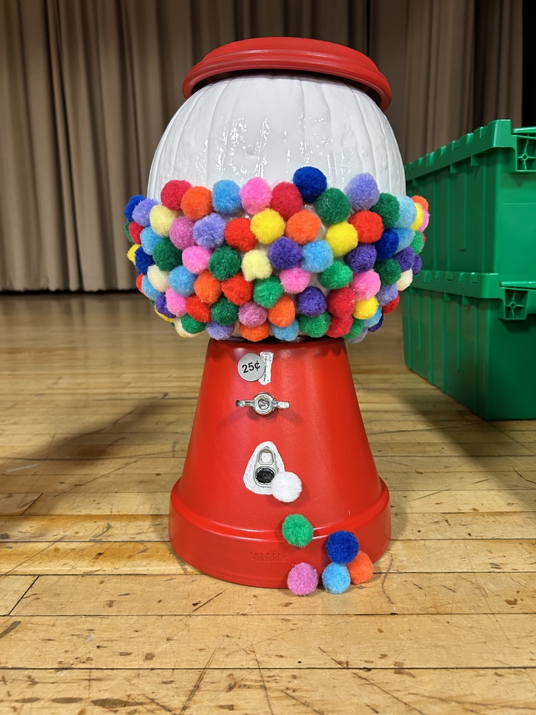 Red machine with a circular base and a round red top filled with colorful pom-poms.