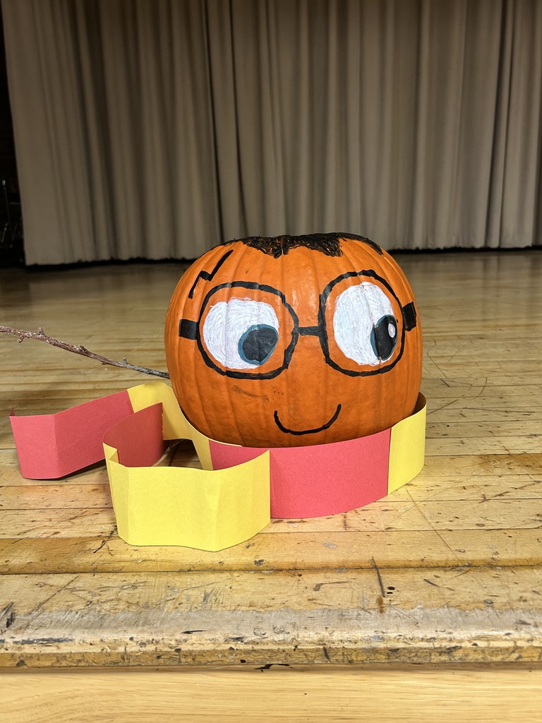 A pumpkin decorated with glasses, a face, and a smile sits on a wooden table.
