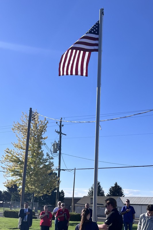 Students and community members watch as the flag is raised at Bridge Academy.