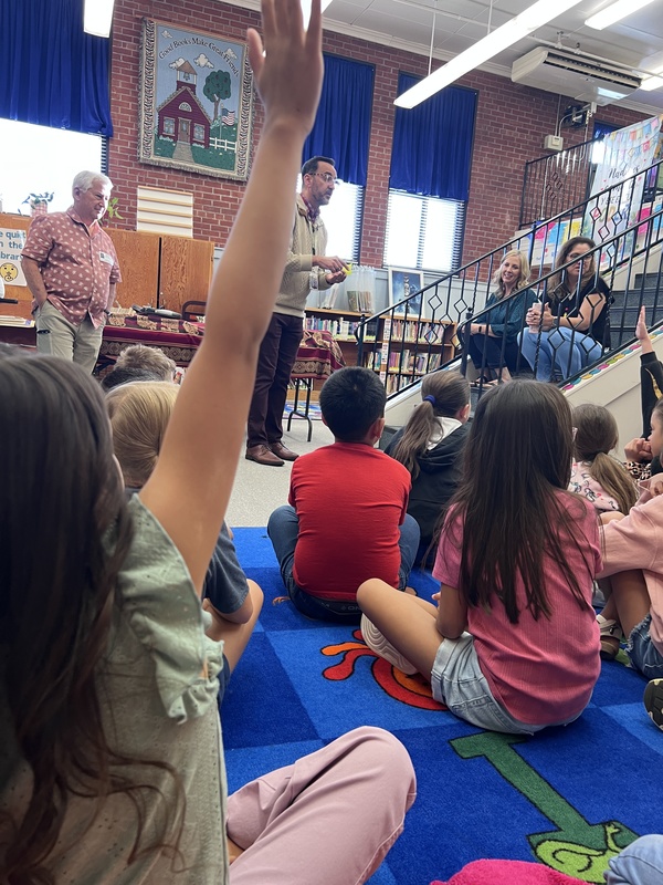 Student raises hand while listening in the library