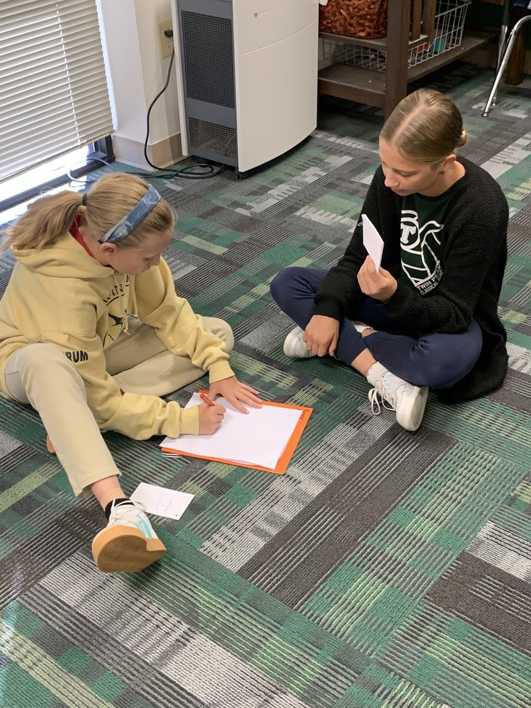 Students sitting on the ground working on math problems.