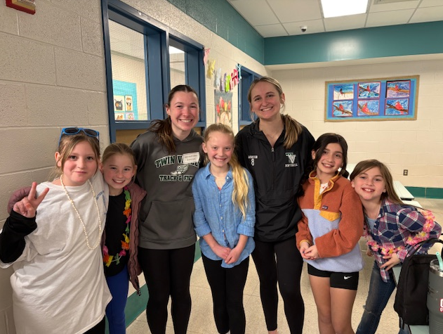 two female high school students with a group of young girl elementary students