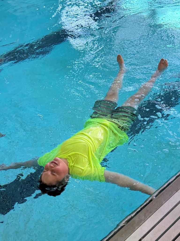 4th grade boy floating in water, looking relaxed and serene.