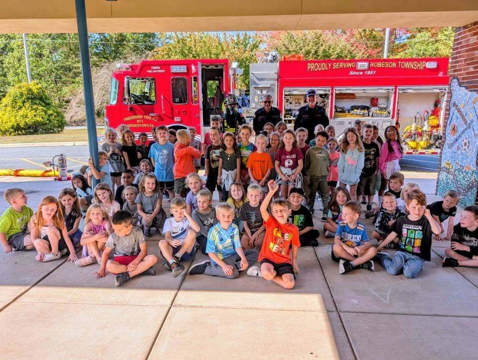 students sitting in front of firetruck