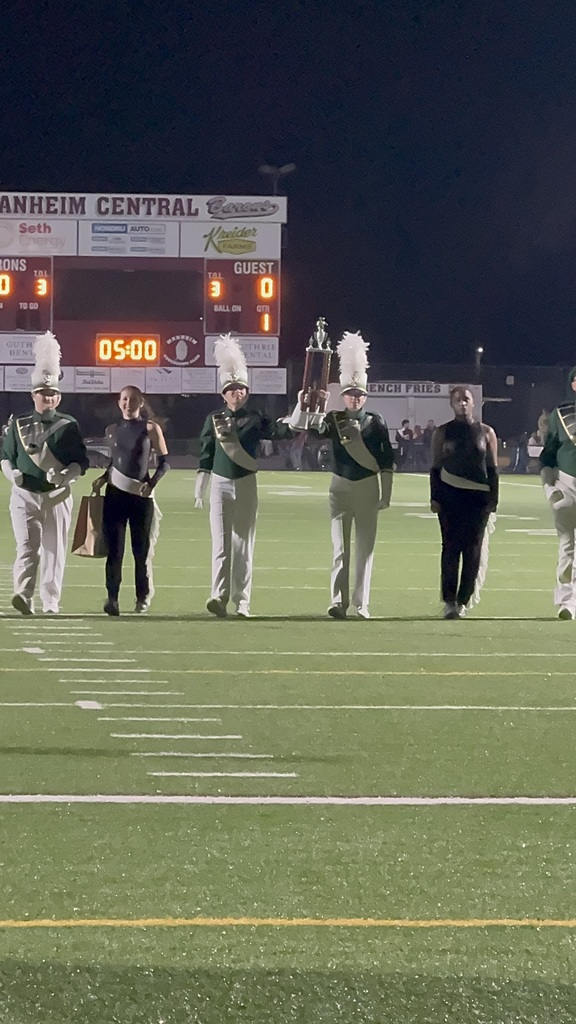 two marching band members holding a gold trophy above their heads in celebration