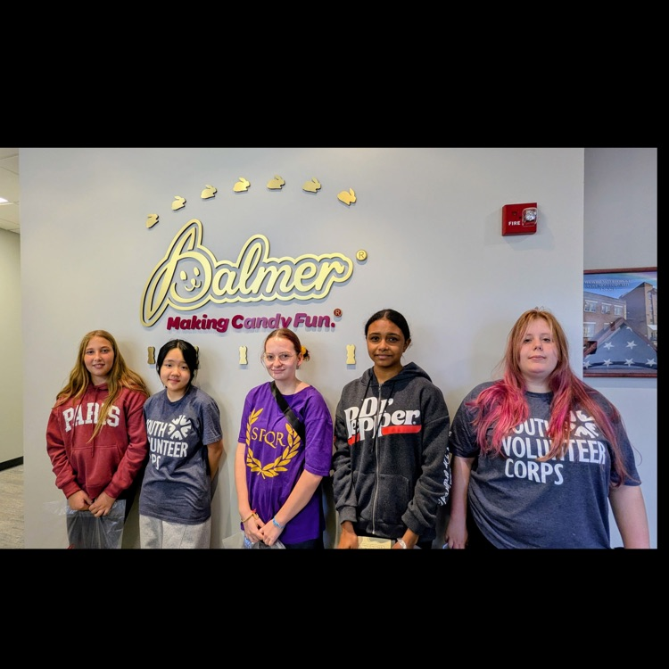 5 students posing in front of the Palmer candies sign