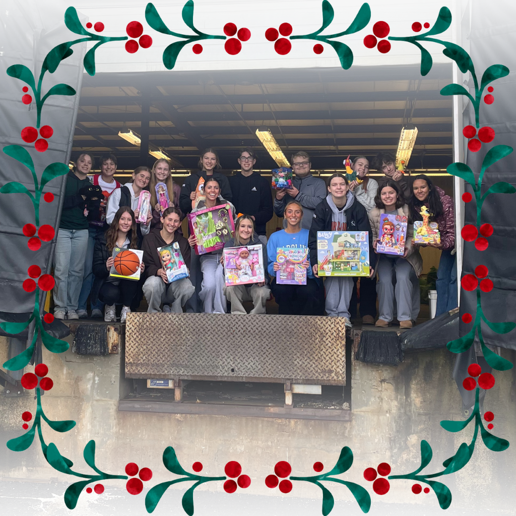 Group of high school students standing at the garage door of a warehouse, each is holding up a toy which will be donated to a child in need.