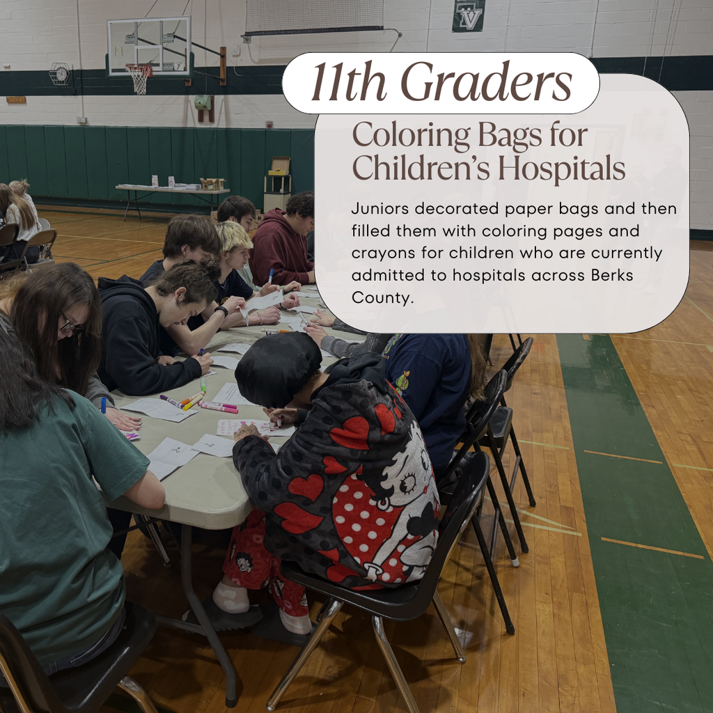 11th grade students sitting at tables in a gym while decorating and coloring paper bags for children in the hospital
