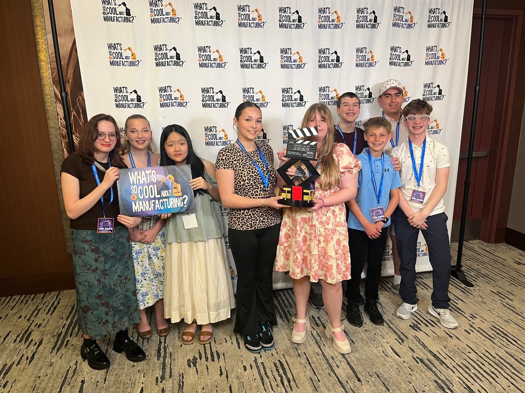 students posing and smiling with award
