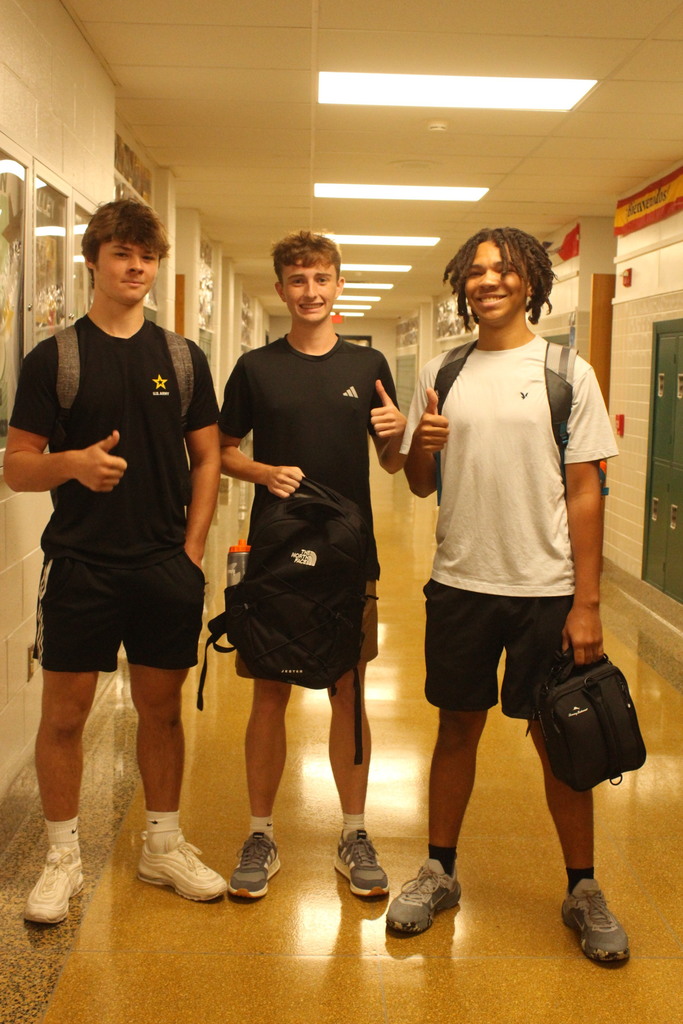 students posing with backpacks and giving a thumbs up