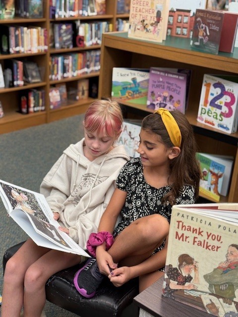 Two girls reading a book in the library