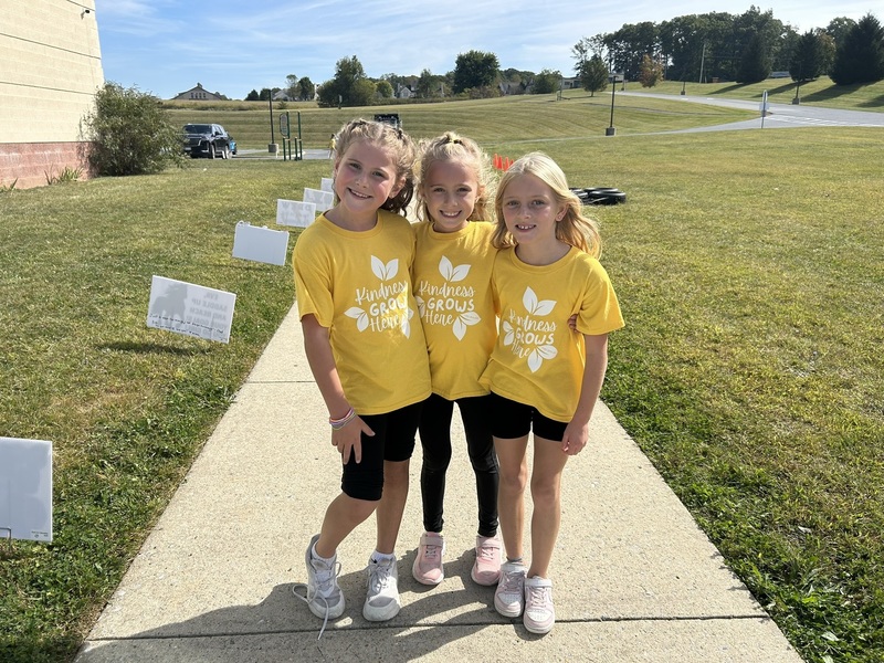 three students posing for a picture in yellow shirts