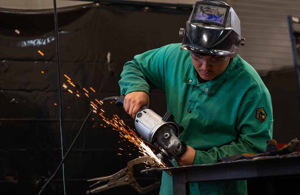 teen boy using grinder on metal with sparks flying