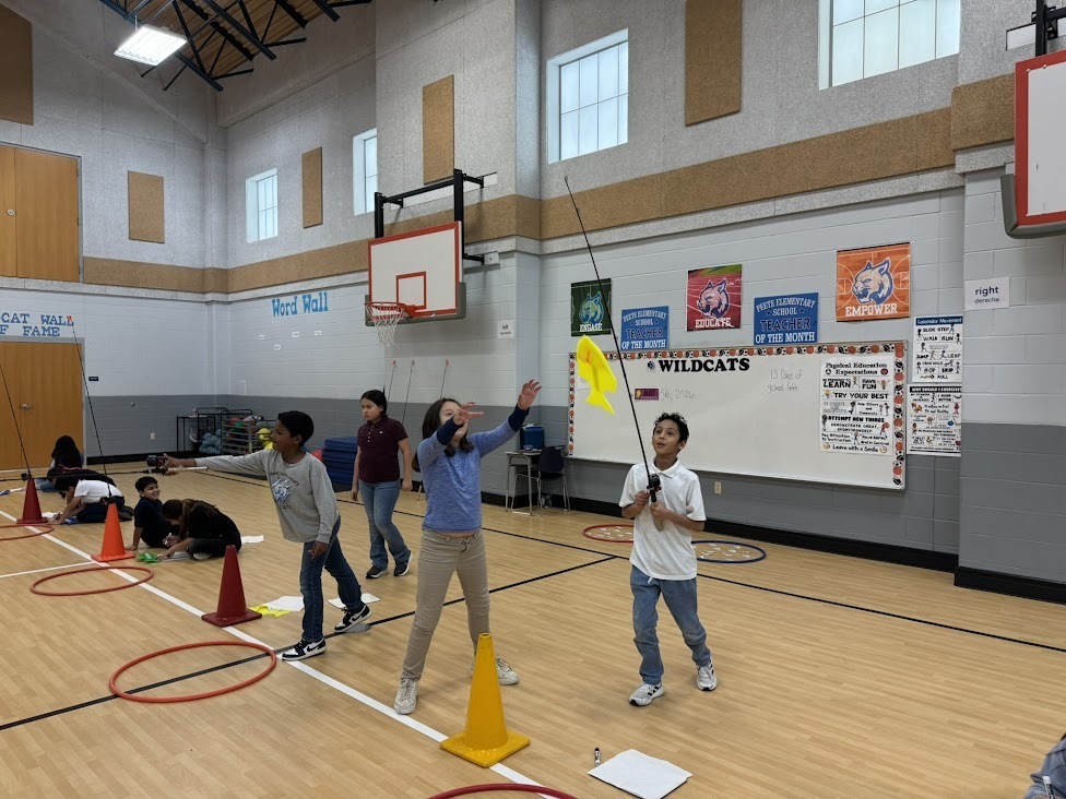 elementary kids in a gym with plastic fish, fishing poles, and hula hoops