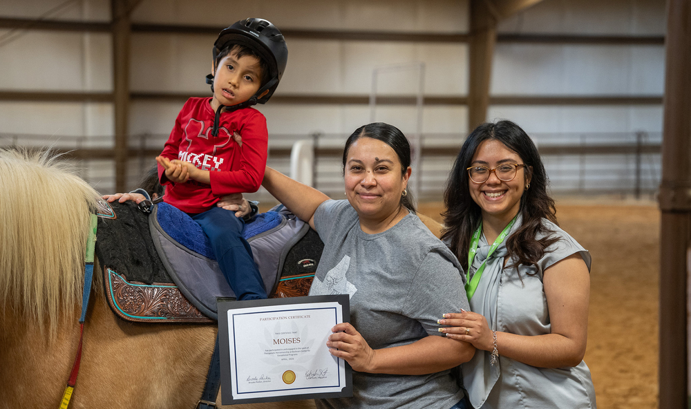 elementary age boy on a horse with two women standing beside them