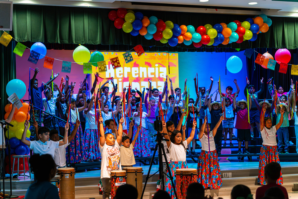 elementary age students in bright colored clothing dancing on stage