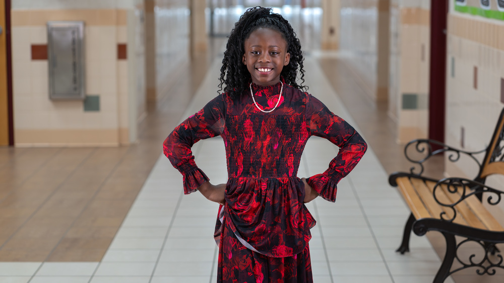 elementary age girl standing in school hallway with hands on her hips