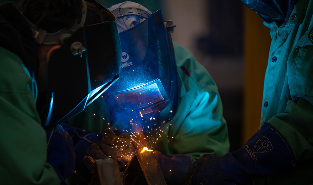 welders with helmets and gloves on and sparks flying