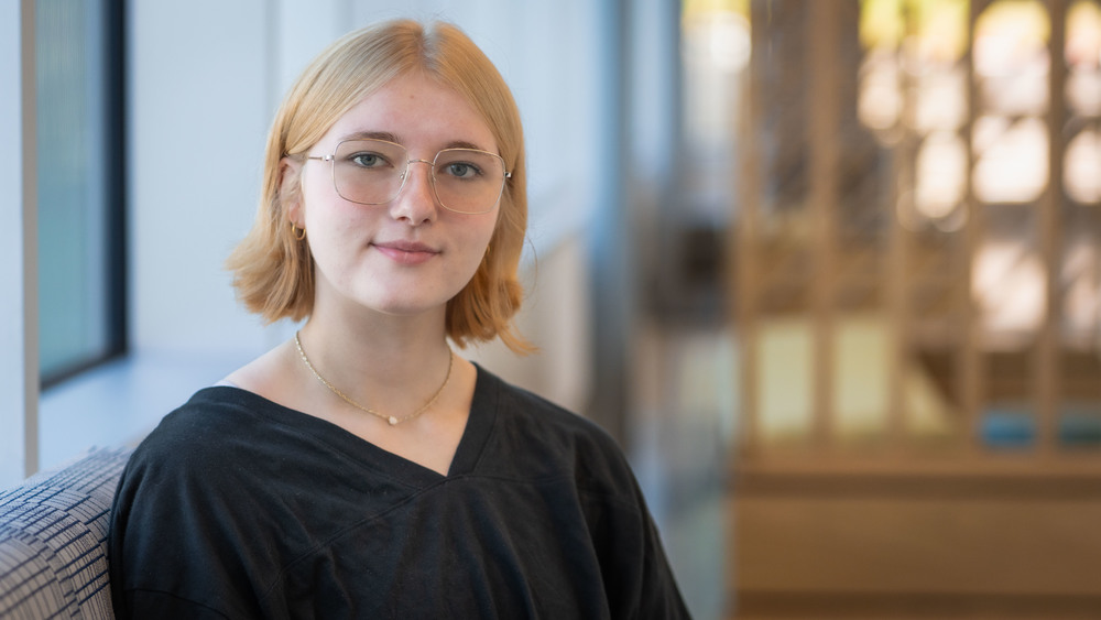 teen girl with short blond hair and glasses sitting on a couch