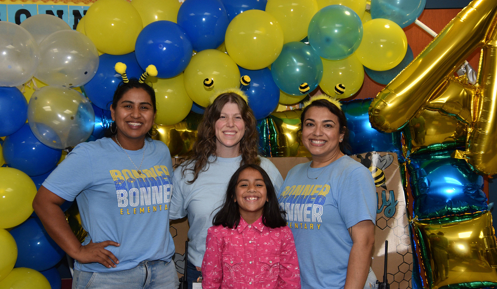 three women and a young girl standing in front of balloons