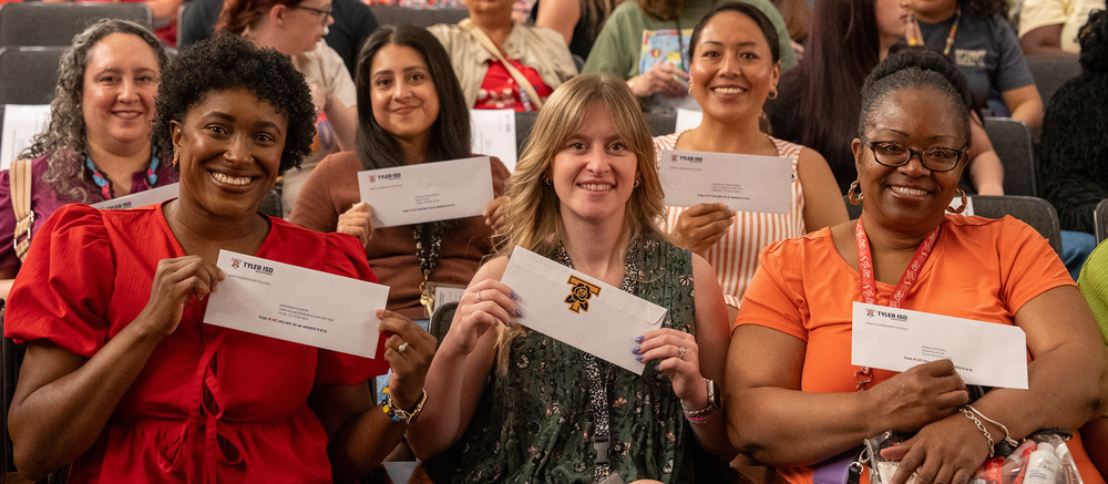women with big smiles holding envelopes with checks