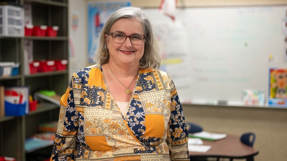 woman wearing yellow pattern dress standing in classroom