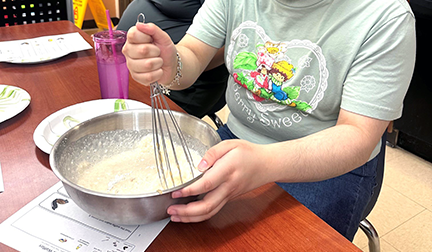 hands stirring batter in a bowl with a whisk