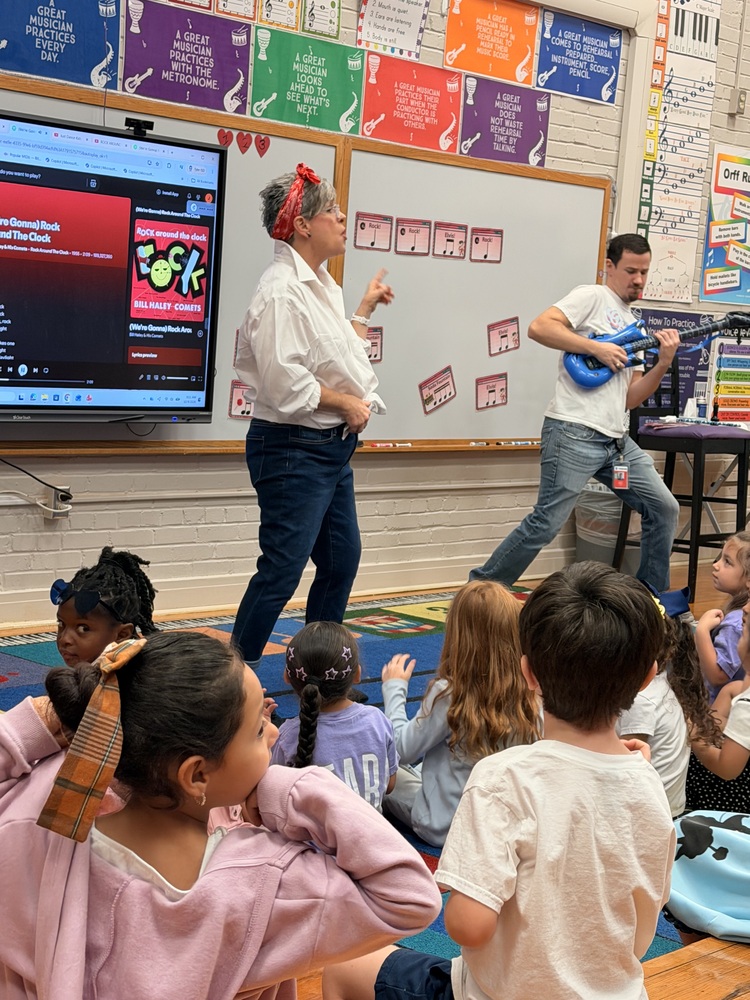 Two teachers singing in front of a group of students for Rock Your School day.