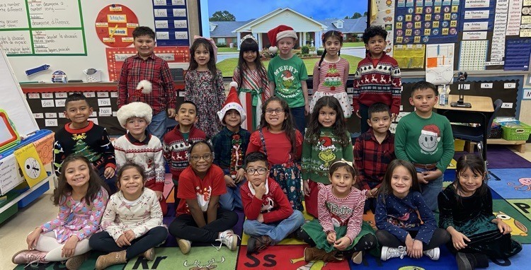 elementary age students wearing Christmas clothes sitting together in classroom
