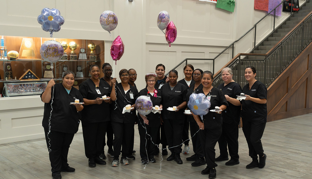 women dressed in black scrubs holding balloons in a hallway
