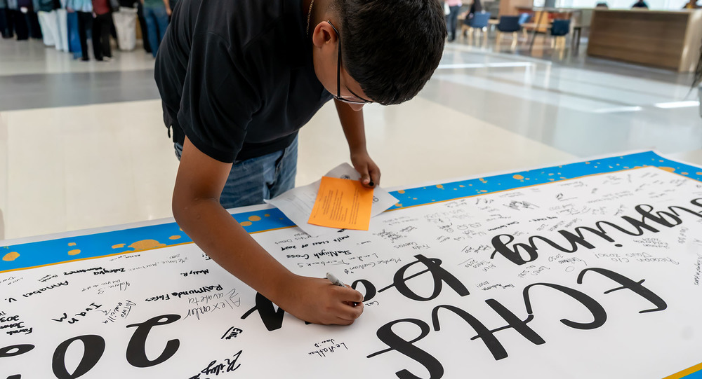 teen boy signing name on a poster